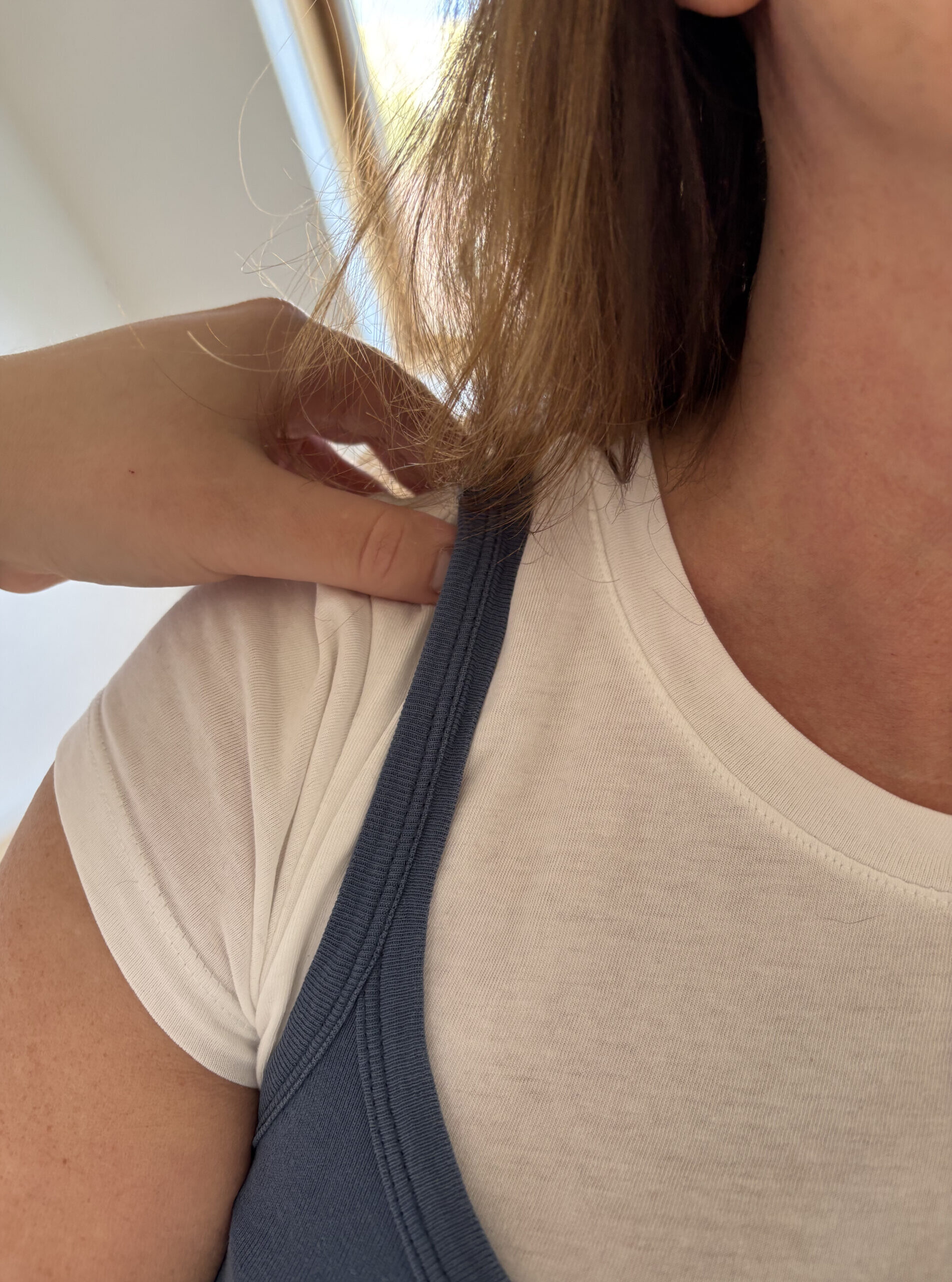 Kinesiologin berührt die Schulter einer Klientin